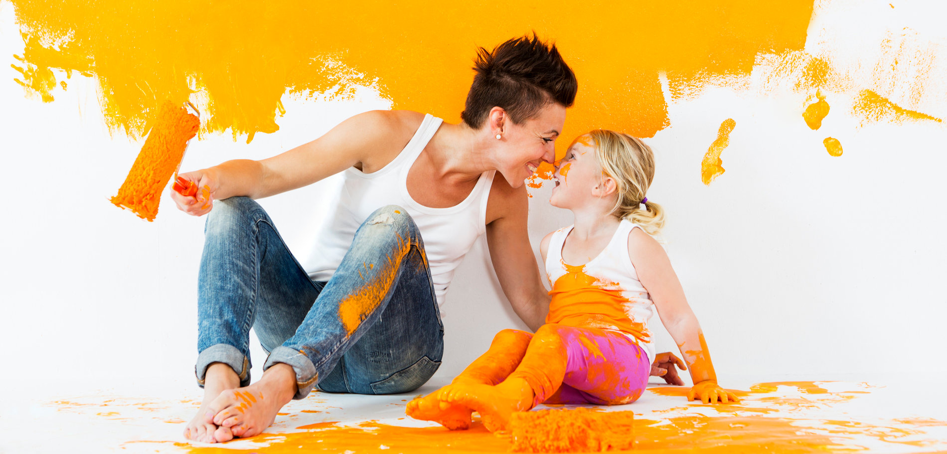 Mutter und Kind streichen eine Wand gelb an